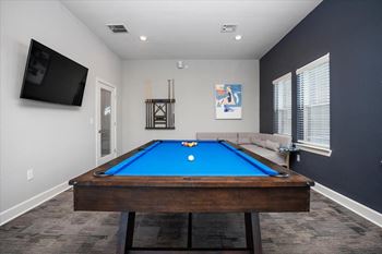 A pool table in a room with a television and a picture on the wall.